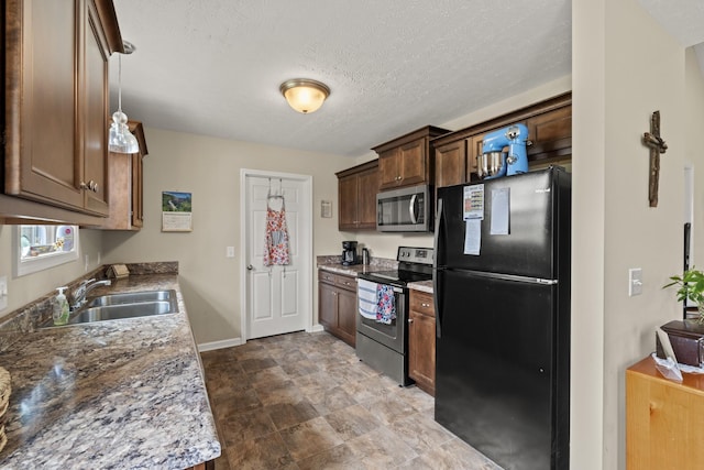 kitchen featuring appliances with stainless steel finishes, a textured ceiling, baseboards, and a sink