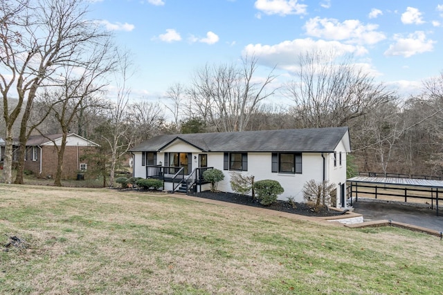 ranch-style home featuring a detached carport, a front yard, a porch, and aphalt driveway