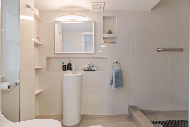 bathroom with toilet, a walk in shower, and tile patterned flooring