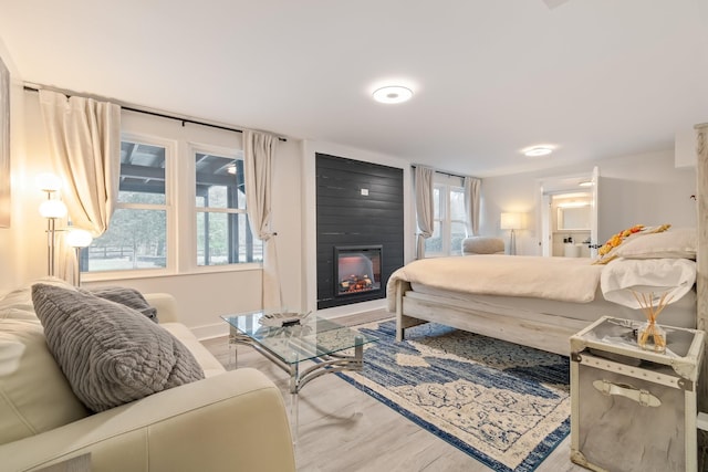 bedroom with wood finished floors and a large fireplace