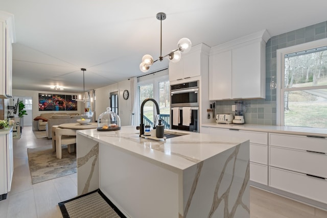 kitchen featuring a sink, an inviting chandelier, double oven, and open floor plan