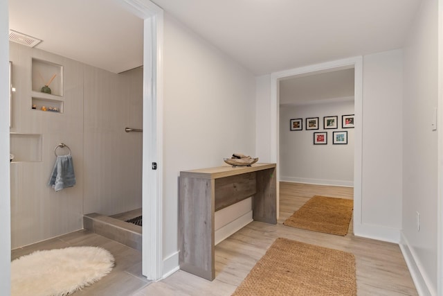 bathroom featuring visible vents, baseboards, built in shelves, and wood finished floors