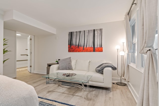 living area featuring baseboards and light wood-style flooring