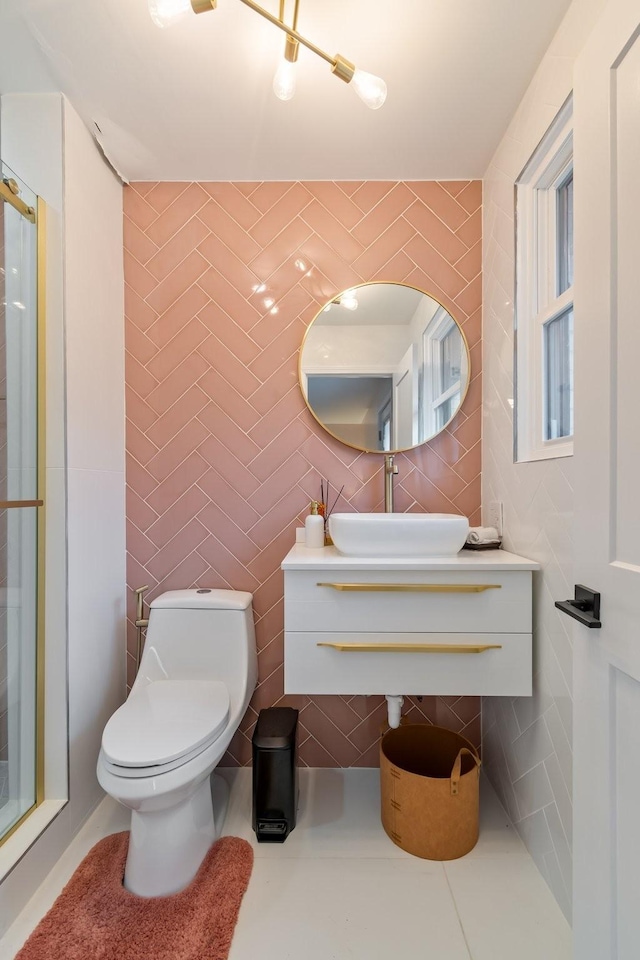 bathroom with toilet, a sink, a shower stall, tile patterned flooring, and tile walls