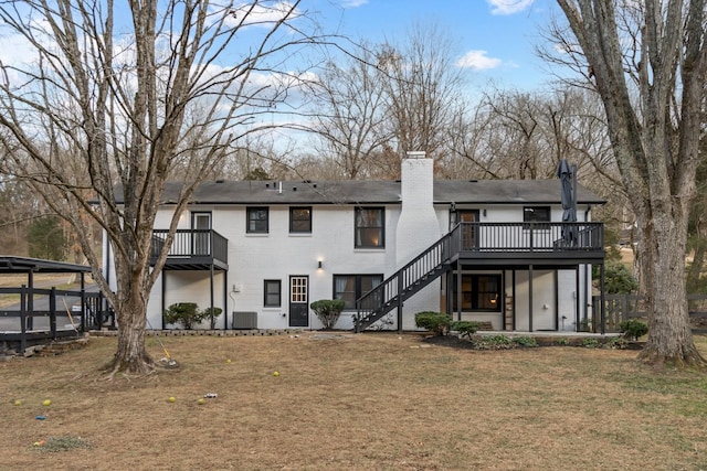 rear view of property featuring stairs, central AC unit, brick siding, a yard, and a chimney