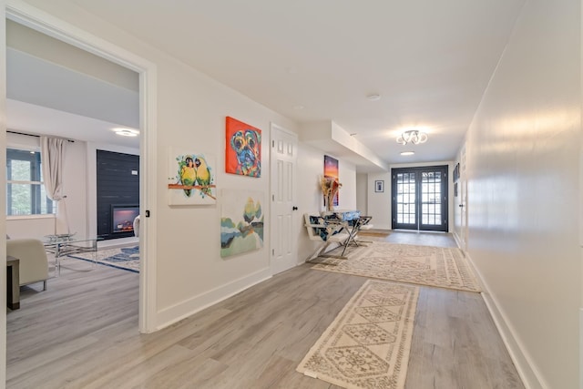 entryway featuring light wood finished floors, baseboards, and a large fireplace
