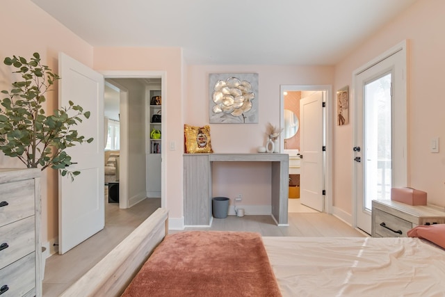 bedroom with ensuite bathroom, baseboards, and multiple windows