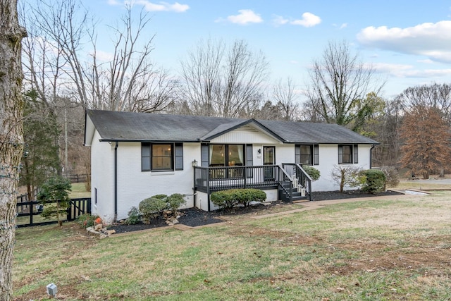 ranch-style home with fence, brick siding, a front lawn, roof with shingles, and a porch