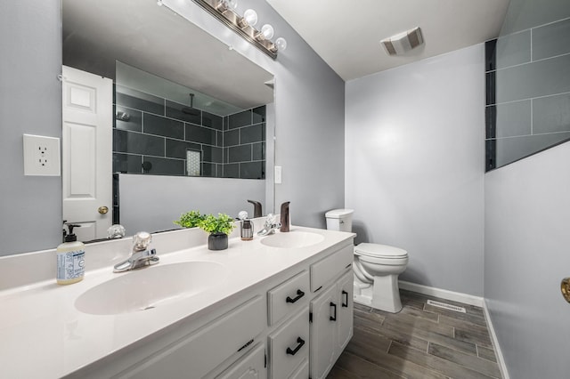 bathroom with visible vents, toilet, baseboards, and a sink