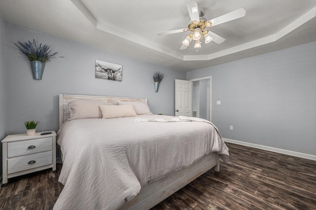 bedroom with a tray ceiling, baseboards, and wood finished floors