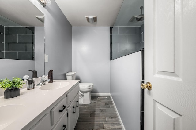 bathroom with visible vents, wood finish floors, a sink, walk in shower, and toilet