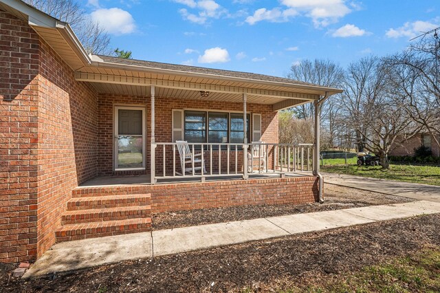 doorway to property featuring brick siding and covered porch