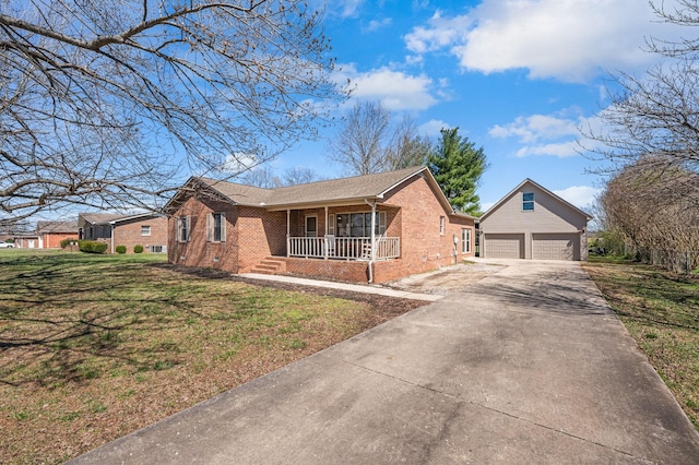 view of front facade with brick siding, covered porch, a garage, an outbuilding, and driveway