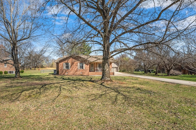 view of property exterior with brick siding, a lawn, and driveway