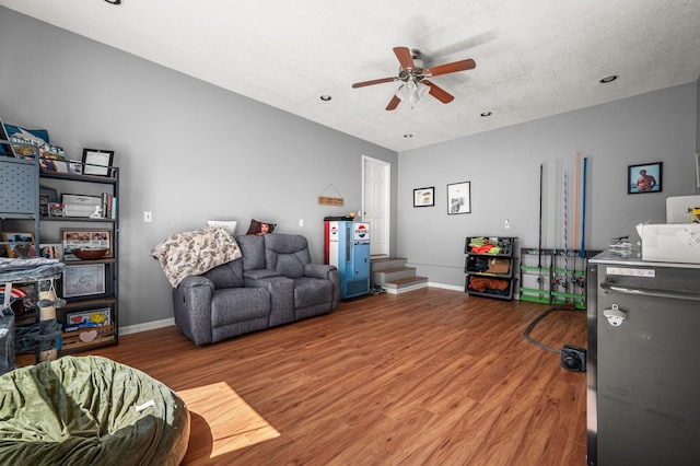 interior space featuring a textured ceiling, wood finished floors, baseboards, and ceiling fan
