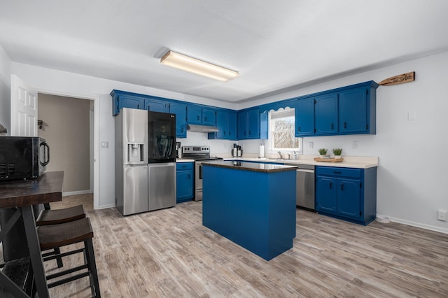 kitchen featuring blue cabinetry, light wood-type flooring, appliances with stainless steel finishes, and under cabinet range hood
