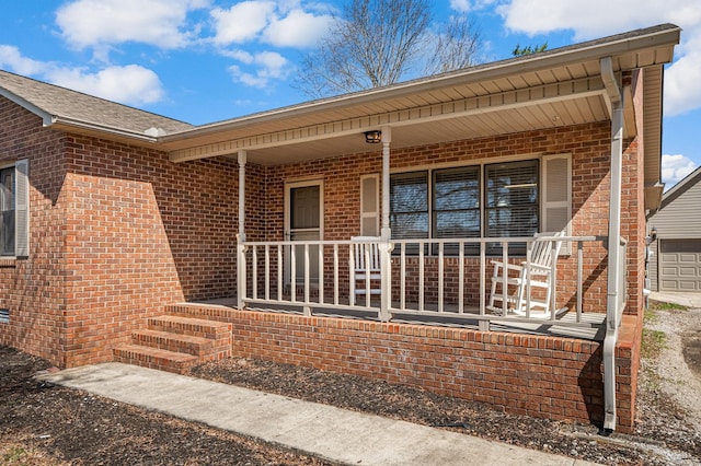property entrance featuring a garage, brick siding, and a porch