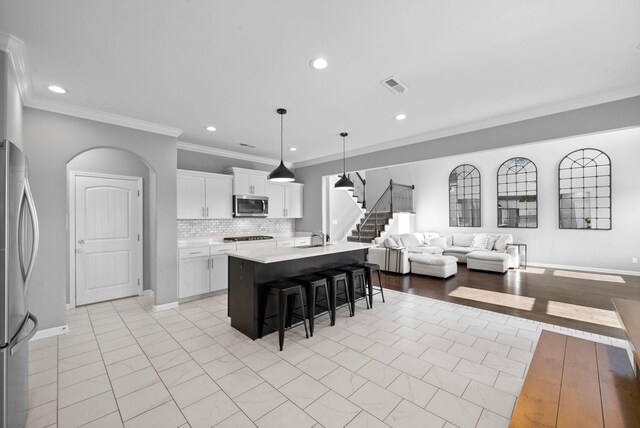 1044 Thrasher Dr, Clarksville, TN 37040 - kitchen with a kitchen bar, visible vents, open floor plan, stainless steel appliances, and arched walkways