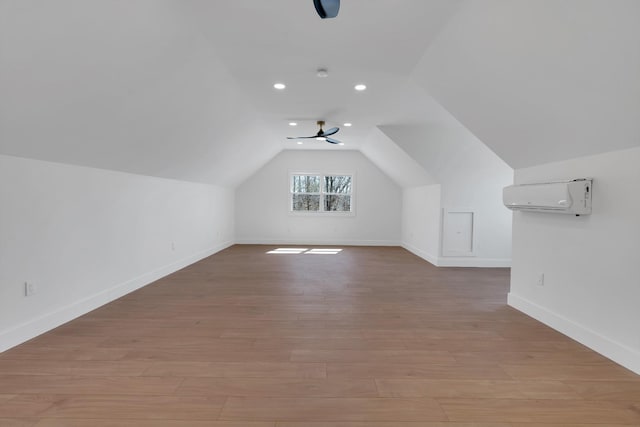 bonus room with a ceiling fan, baseboards, light wood-style flooring, an AC wall unit, and vaulted ceiling