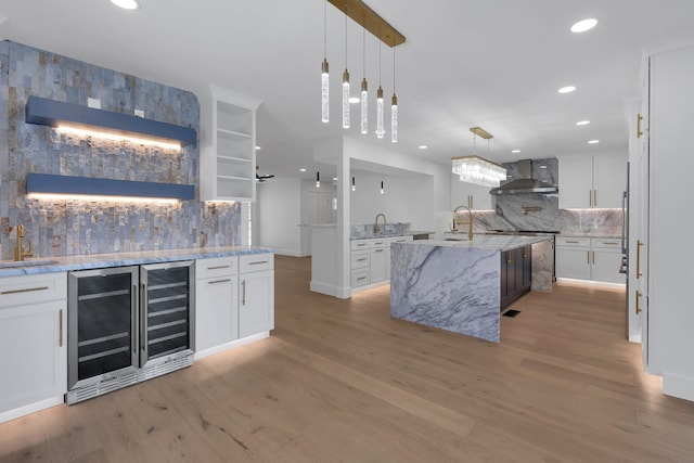 kitchen featuring open shelves, wall chimney range hood, light wood-type flooring, and white cabinets