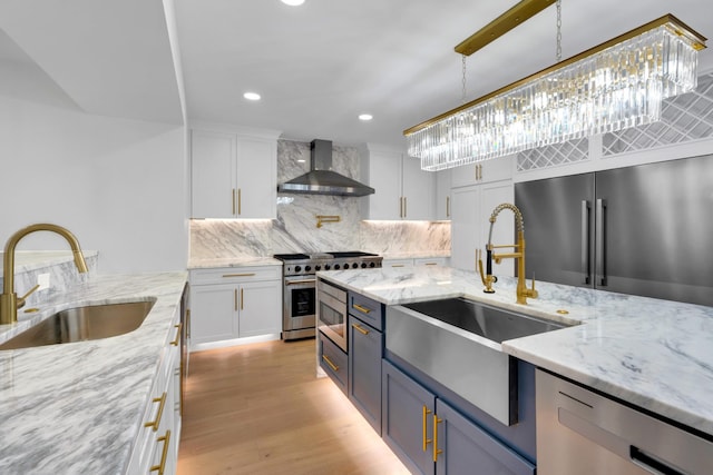 kitchen featuring a sink, high end appliances, wall chimney exhaust hood, and white cabinets