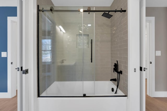 bathroom featuring baseboards, shower / bath combination with glass door, and wood finished floors