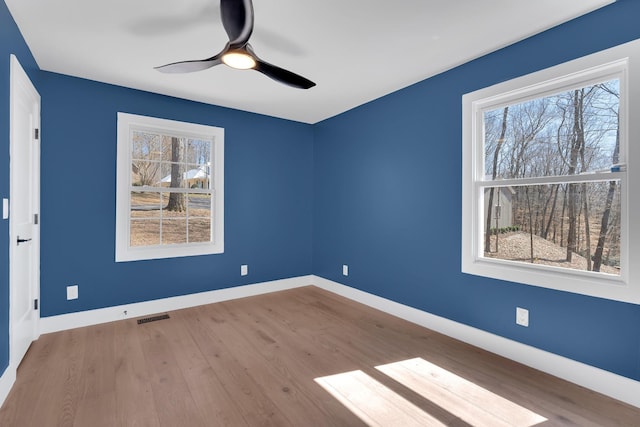 spare room with a ceiling fan, wood finished floors, baseboards, and visible vents