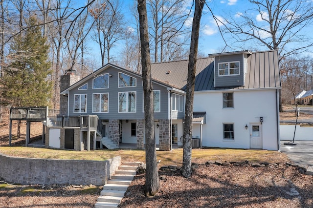 view of front facade featuring a deck, a front lawn, a standing seam roof, stairway, and metal roof