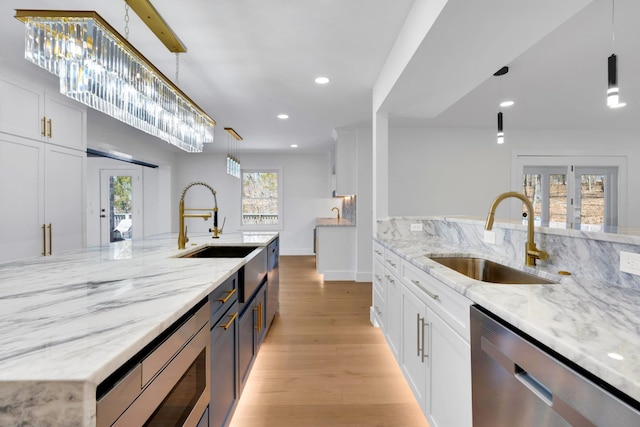 kitchen with a sink, french doors, light wood-style floors, appliances with stainless steel finishes, and white cabinets