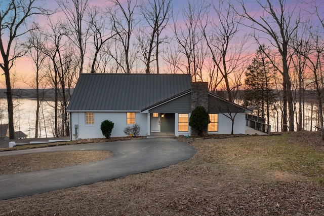 view of front of home featuring aphalt driveway, metal roof, and a chimney