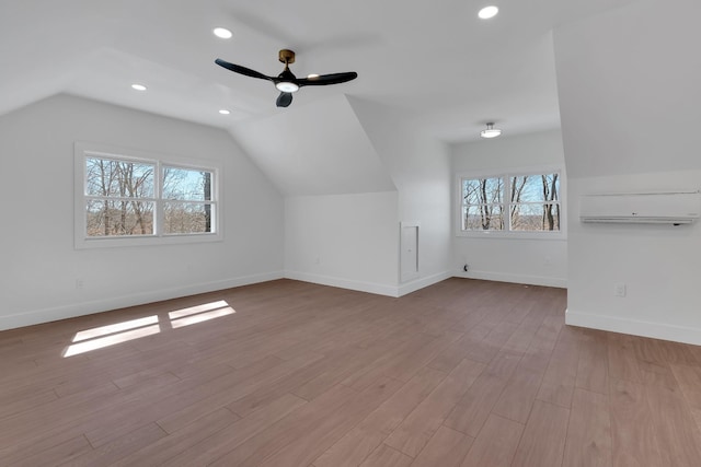 additional living space featuring lofted ceiling, wood finished floors, baseboards, and a healthy amount of sunlight