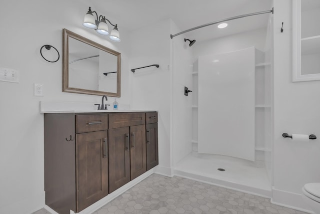 full bath with toilet, vanity, a shower, and baseboards