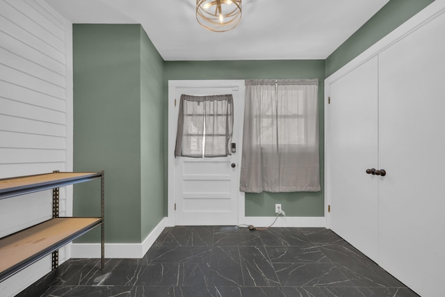 foyer with marble finish floor and baseboards