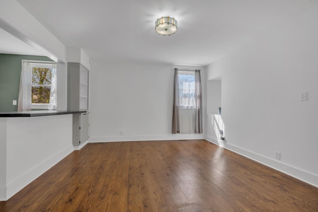 unfurnished living room with wood finished floors and baseboards