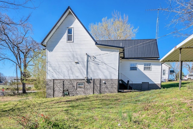 back of house with metal roof and a yard