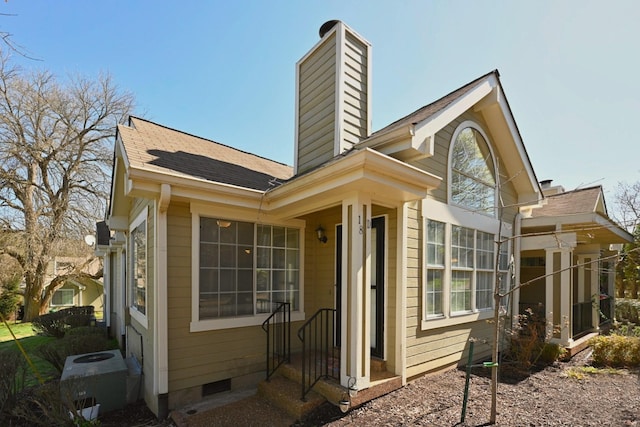 exterior space featuring crawl space, central AC, a chimney, and roof with shingles