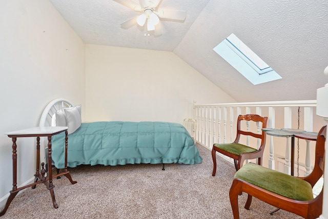 carpeted bedroom featuring ceiling fan, lofted ceiling with skylight, and a textured ceiling