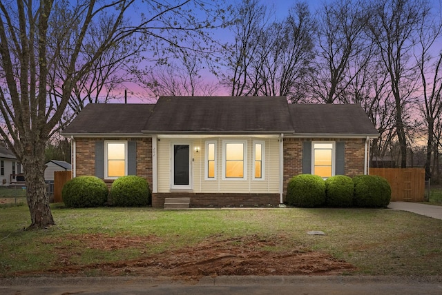 view of front of property with a yard, brick siding, entry steps, and fence