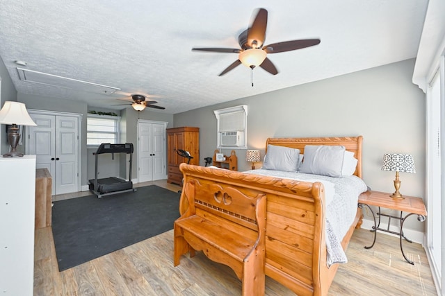 bedroom featuring cooling unit, wood finished floors, attic access, ceiling fan, and a textured ceiling