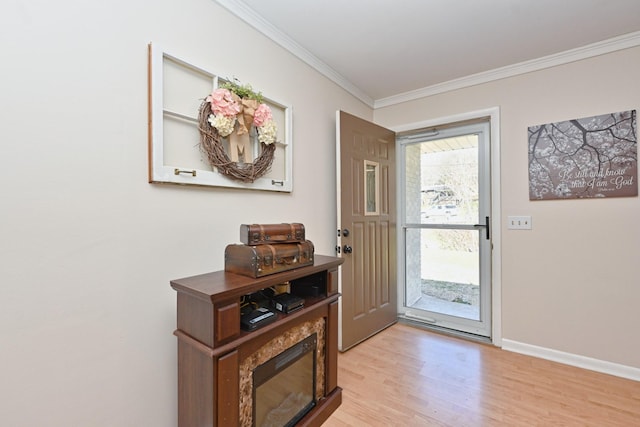 entryway with light wood-type flooring, baseboards, and ornamental molding