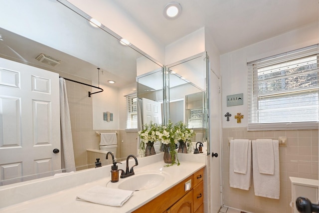 bathroom featuring vanity, a shower with curtain, visible vents, wainscoting, and tile walls