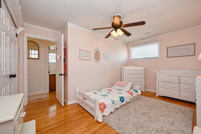 bedroom with light wood finished floors, ceiling fan, crown molding, and baseboards