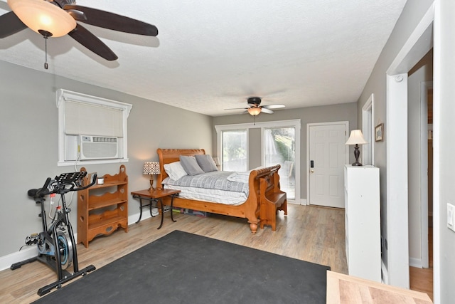 bedroom featuring a ceiling fan, wood finished floors, baseboards, a textured ceiling, and access to outside
