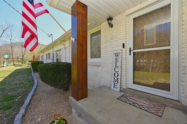 entrance to property with a porch and brick siding