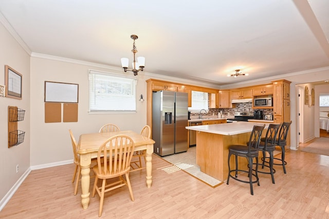 kitchen featuring a sink, decorative backsplash, stainless steel appliances, crown molding, and a notable chandelier