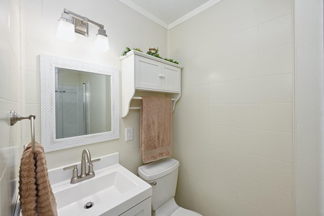 bathroom featuring vanity, crown molding, toilet, and tile walls