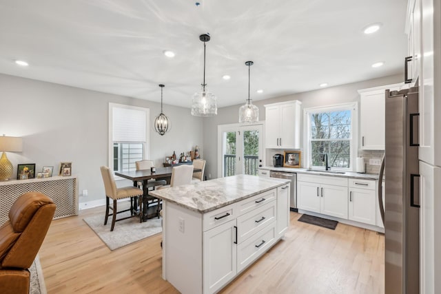 kitchen with open floor plan, light wood finished floors, a sink, and appliances with stainless steel finishes