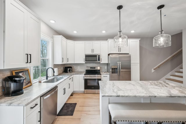 kitchen featuring a sink, a kitchen breakfast bar, light wood-type flooring, stainless steel appliances, and decorative backsplash