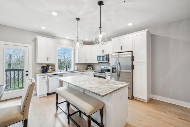 kitchen with white cabinets, a sink, stainless steel appliances, and decorative backsplash