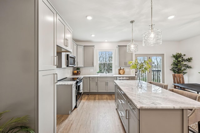 kitchen featuring gray cabinetry, a kitchen bar, appliances with stainless steel finishes, and a sink